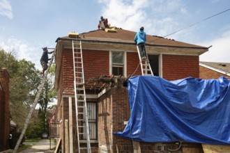 Detroit, Michigan - Workers re-roof a house they are remodeling in the Morningside neighborhood
