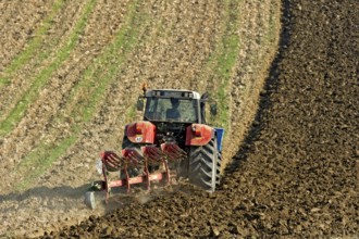 Harvested grain field being turned into a field by Steyr tractor with plough, Hohenpolding, Erding,
