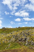 Volcanic rock, overgrown with moss, sparse vegetation, volcanic landscape, cumulus, text free