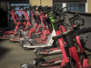 Many rental e-scooters parked on a pavement in Wuppertal, Germany