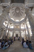 Indian woman praying between the white marble pillars in the Adinath temple in Ranakpur, Jain