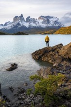 Young man on the shore of the blue lake Lago Pehoe in the evening light, Cuernos del Paine mountain