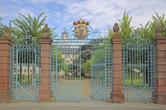 Gate entrance with metal gate, decorations and coat of arms, white tower, wrought ironwork,
