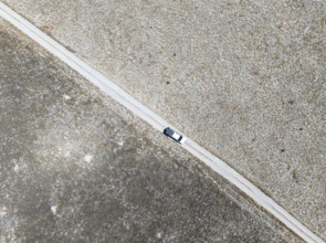 Off-road vehicle driving on a sandy track through a vast dry landscape with yellow grass, Top Down,