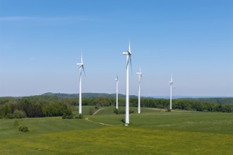 Wind turbines on a green field surrounded by forest under a blue sky, Swabian Alb,