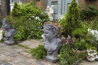 House entrance with blooming flowers, conifers and stone busts, Old Town, Husum, North Frisia,
