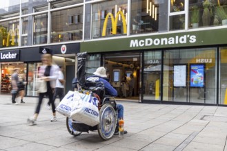 A man in a wheelchair in the Königstraße pedestrian zone in front of a branch of the McDonald's