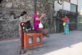 Indian woman holding tea lights in the air at a fire hydrant, Govind Dev Ji Hindu temple in the old