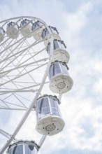 Close-up of a Ferris wheel and its gondolas under a cloudy sky, Ferris wheel construction for the