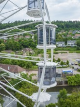 View from a Ferris wheel onto a cityscape with lots of greenery and houses, Ferris wheel
