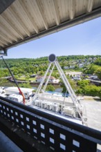 A Ferris wheel seen from above, surrounded by green landscape and buildings, Ferris wheel