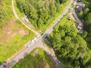 A railway bridge leads over a road, surrounded by forest and vehicles, construction of the Hermann