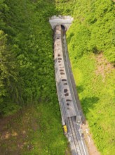 View from above of a railway tunnel surrounded by dense forests, construction of the Hermann Hesse
