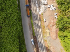 View of street scene with railway tracks and a car through dense forest, construction of the