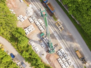 A large crane on a construction site next to rails and building materials, construction of the