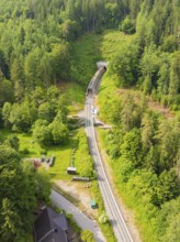Aerial view of a railway tunnel running through a green, wooded landscape, construction of the
