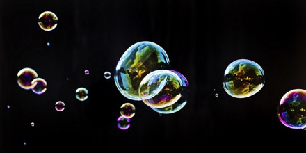 Iridescent soap bubbles in the colours of the rainbow against a black background, Recklinghausen,