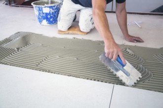 Tile laying: Tiler lays large light-coloured floor tiles