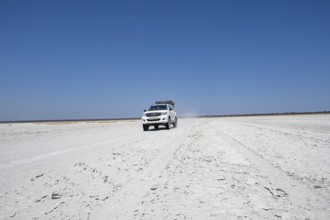 Off-road vehicle driving on a wide empty salt pan, Makgadikgadi Salt Pans, Botswana