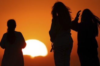 People watching the sun set on the horizon from the summit of the Großer Feldberg in the Taunus,