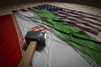 Large hammer, american and Iranian flags resting on desert sand