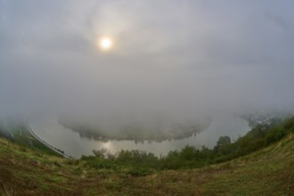 A river is covered by fog while the sun shines through the clouds, summer, Rhine bend Boppard,