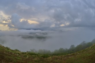 Hills with dense fog enveloping the landscape, under a cloudy morning sky, summer, Rhine bend