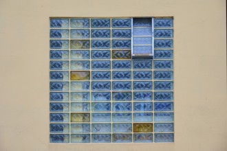 Rectangular window with blue glass blocks in a geometric pattern on a beige wall, Rüdesheim am