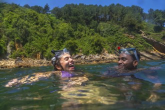 Tourists wearing snorkeling masks, laughing joyfully while enjoying a sunny summer vacation in the