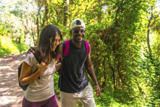 Happy couple hiking together, enjoying a scenic walk along a lush green forest trail, surrounded by