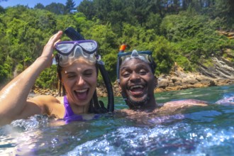 Interracial couple enjoying a fun snorkeling adventure in the vibrant ocean, laughing and sharing