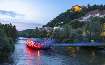 Night-time view of the Murinsel floating island on the river Mur with Schlossberg castle hill in