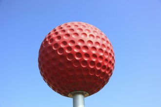 Large red golf ball to advertise a golf course