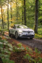 A modern car drives on a forest road in the sunlight through green trees, Deer E- CarSharing,