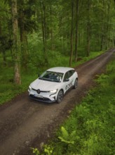A car drives along a quiet forest path surrounded by dense green forest, Deer E- CarSharing,