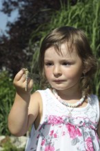 Girl, toddler looking at freshly hatched Southern Hawker (Aeshna cyanea) dragonfly on her finger at