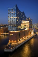 Aerial view of the Elbphilharmonie at blue hour with illuminated windows and view over the