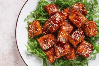 Fried salmon slices, teriyaki with sesame seeds, with arugula salad, top view