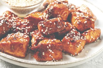Fried pieces of salmon teriyaki with sesame seeds, top view