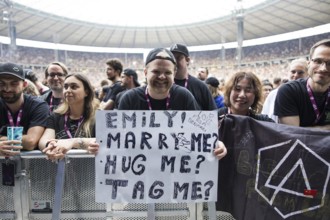 A fan holds a poster with the words Emily! Marry me? Hug me? Tag me? (Emily! Marry me? Hug me? Link