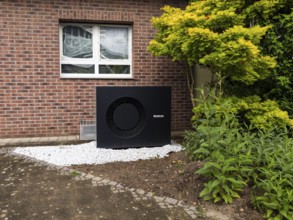 A black heat pump in a front garden in Hilden, Germany