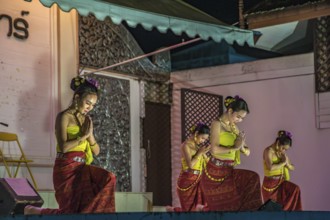 Traditional Thai dancers perform on a lighted stage at the night market in downtown Chiang Rai,