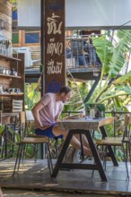 Restaurant customer reading a book while waiting for his order at the Akha Cottage restaurant and