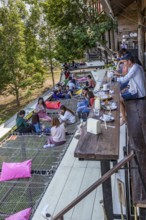 Customers eat, drink and relax on a net suspended over the hillside at the Akha Cottage restaurant
