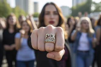 Defiant female fist with bold engraved ring at feminist rally. Protest against patriarchy and