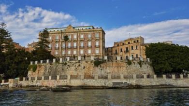 Elevated wall with historic buildings and lush vegetation in the coastal area, boat trip around the