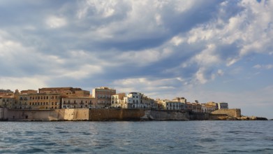City along the coast with high clouds on the horizon, boat trip around the island of Ortigia, Isola