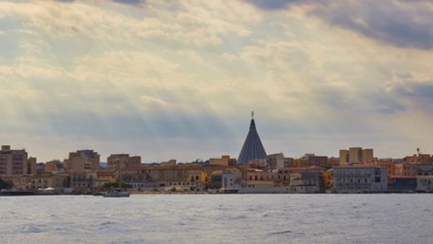 City with striking church spire under a cloudy sky over the sea, boat trip around the island of