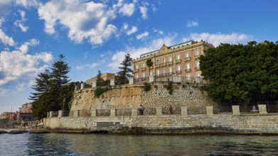 Impressive building on a cliff with lush trees and sunny sky, boat trip around the island of