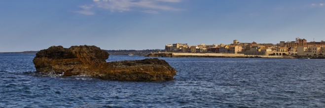 Coastal cliffs in the foreground with a town and blue sky in the background, boat trip around the